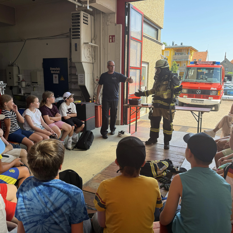 Feuerwehrmann präsentiert sich in voller Montur vor Schüler:innen